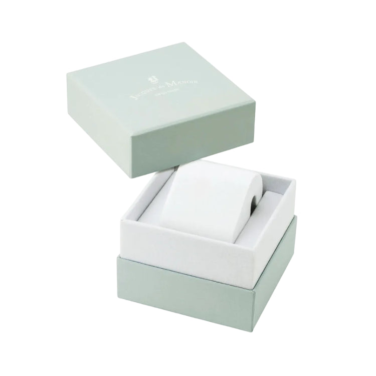 A white cylindrical watch or accessory roll displayed inside an open square presentation box with a pale mint green lid resting above it on a white background.