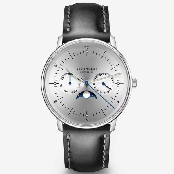 A Sternglas automatic moonphase watch with a silver dial, black leather strap, and blue hands, shown on a light gray background.