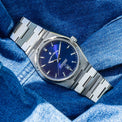Silver watch with a blue face on a blue textured background