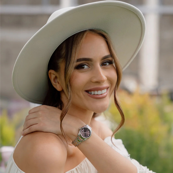 Woman wearing a white hat and white top with a blurred outdoor background