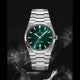 Silver watch with a green dial on a dark background
