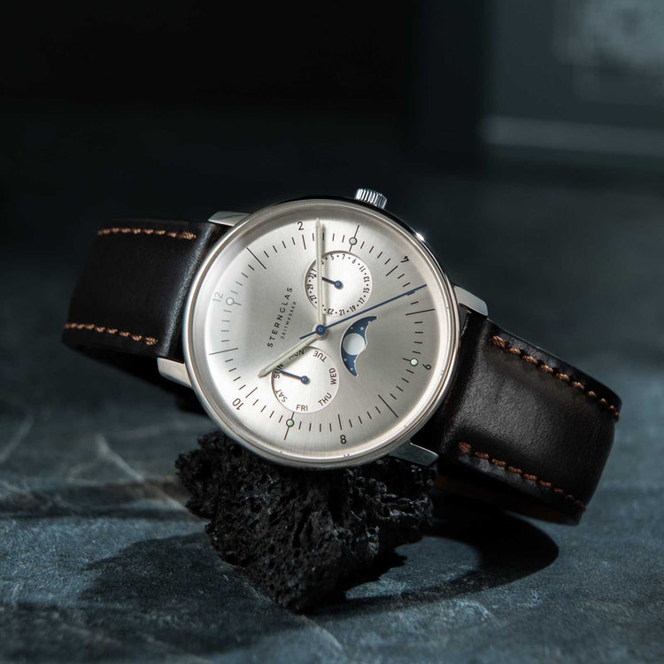 Watch with a brown leather strap on a dark textured surface