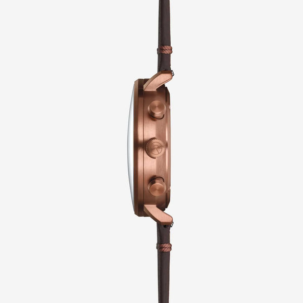 A close-up side profile of a smartwatch with a metallic rose gold case and a dark brown leather strap, shown against a solid light gray background.