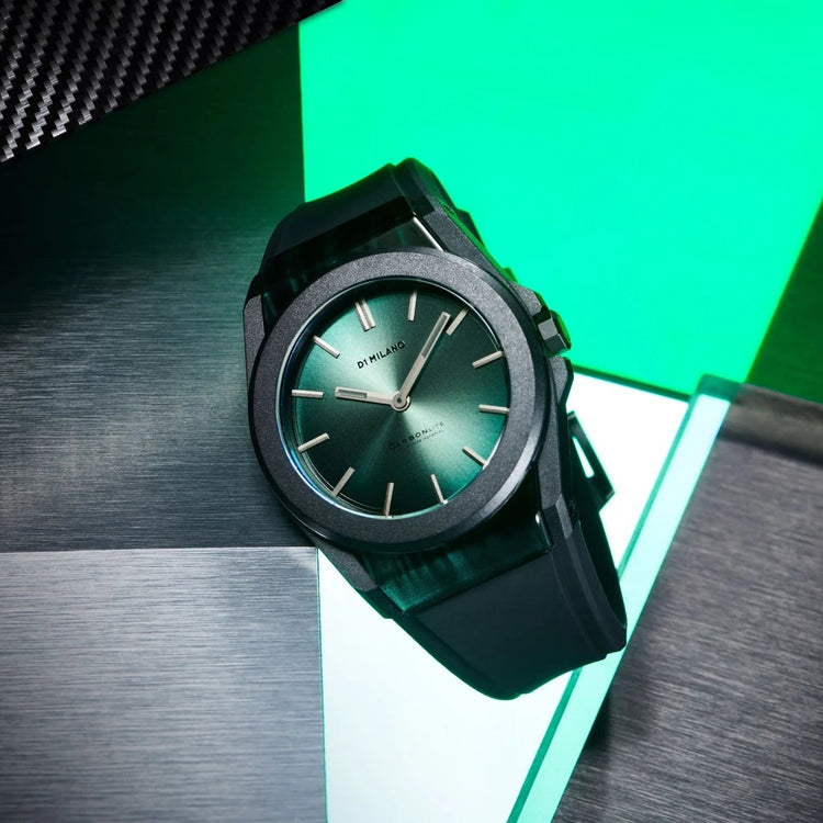 A black digital watch with a dark green dial and matching green-tinted strap, resting on a geometric surface with black and bright green panels.