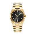 A gold stainless steel Jacques du Manoir watch with a black dial and a date display, on a metal bracelet.