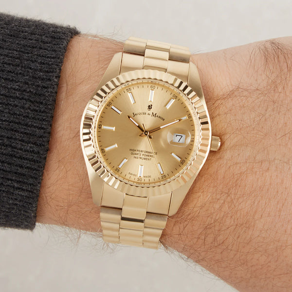 Gold wristwatch on a person's wrist with a neutral background