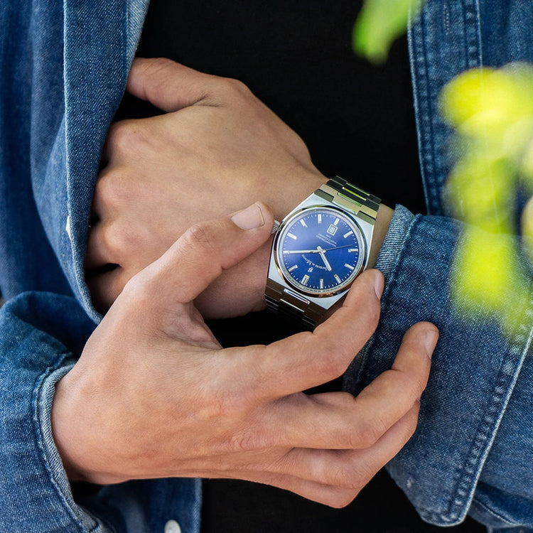 Person wearing a blue watch with a denim jacket