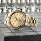 Gold watch with a detailed face on a textured surface